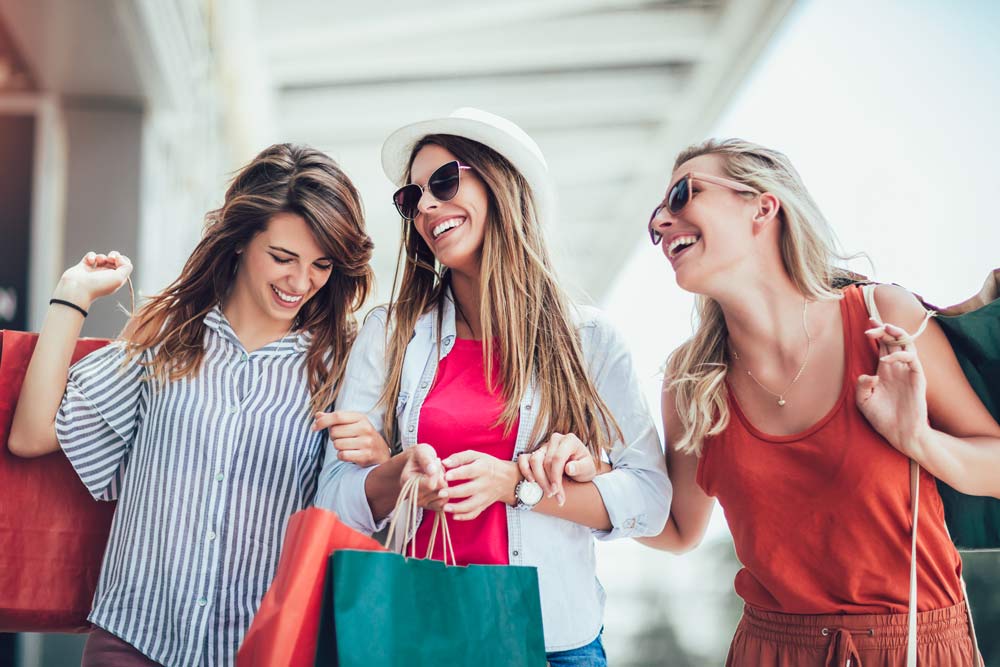 three women smiling and holding shopping bags